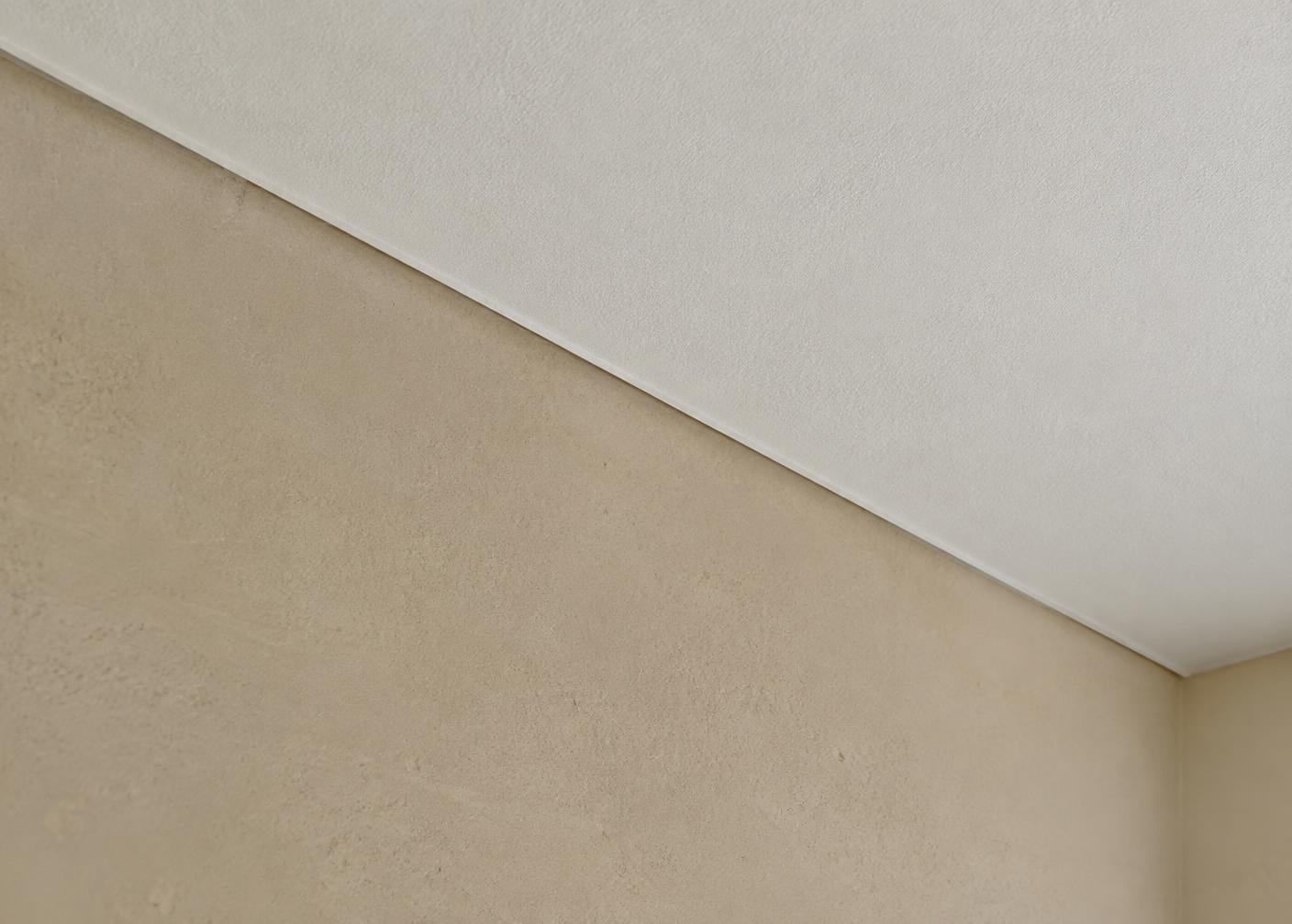 Detail einer fein verputzten Wand mit präzisem Anschluss zur Decke
